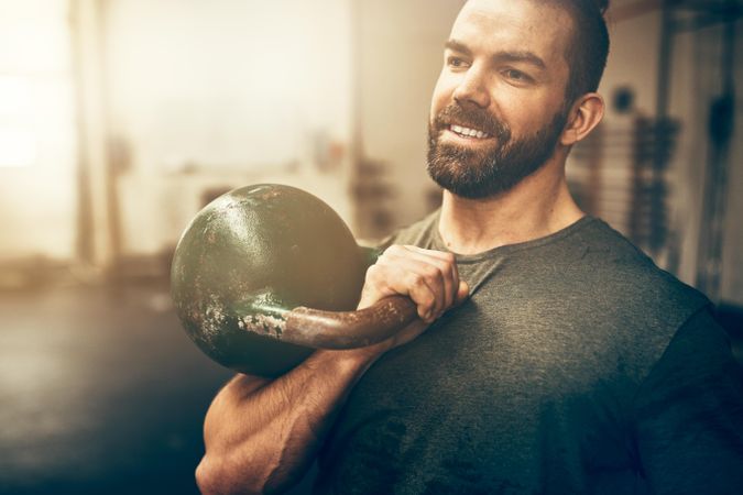 Man smiling while holding kettlebell to chest