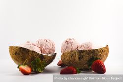 Side view of two coconut shells with delicious ice cream and strawberry fruit 4ABZmb