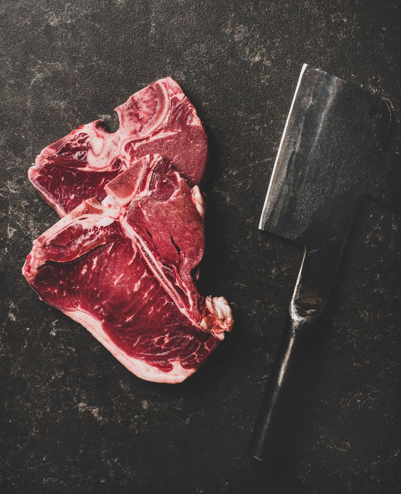Two T-bone steaks with cleaver on butchers block
