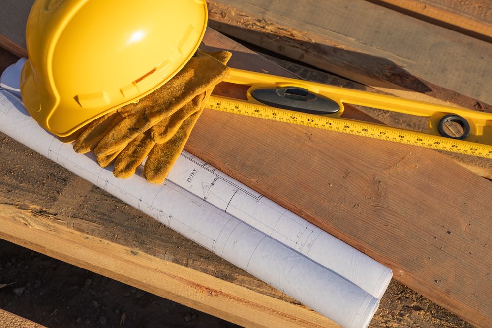 Abstract of Constrcution Hard Hat, Gloves, Level and House Plans Resting on Wood Planks