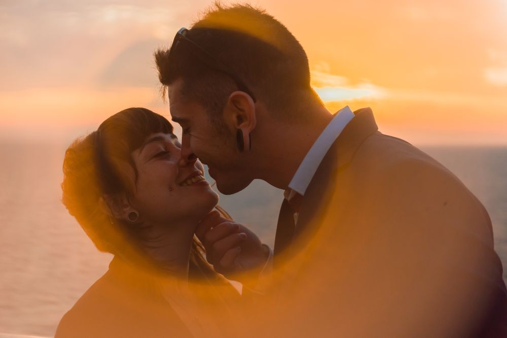Young people kissing in sunset light on ship