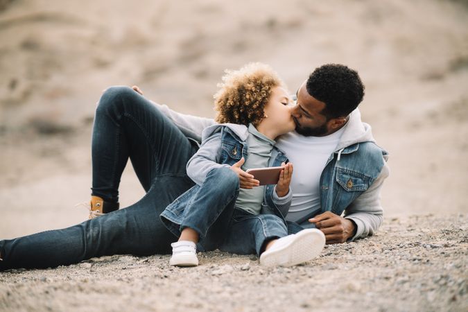Black father relaxing in nature with ethnic kid