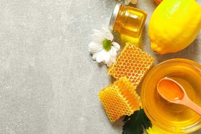 Flat lay with honey, flowers and fruits on grey background, copy space