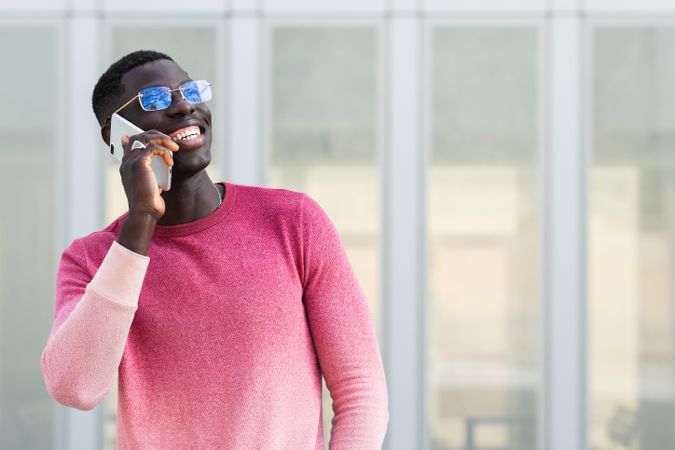 Cheerful Black businessman in eyewear talking on smartphone