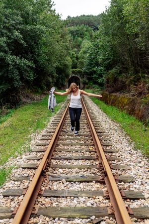 Woman walking along railway though greenery part of road