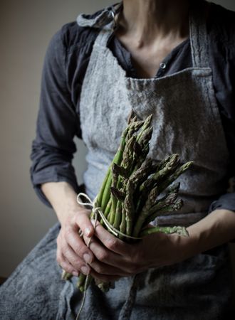 Faceless woman holding bundle of green asparagus