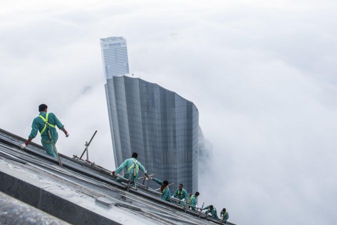 Top view of workers attached to a skyscraper under construction above the clouds in in Dubai, UAE