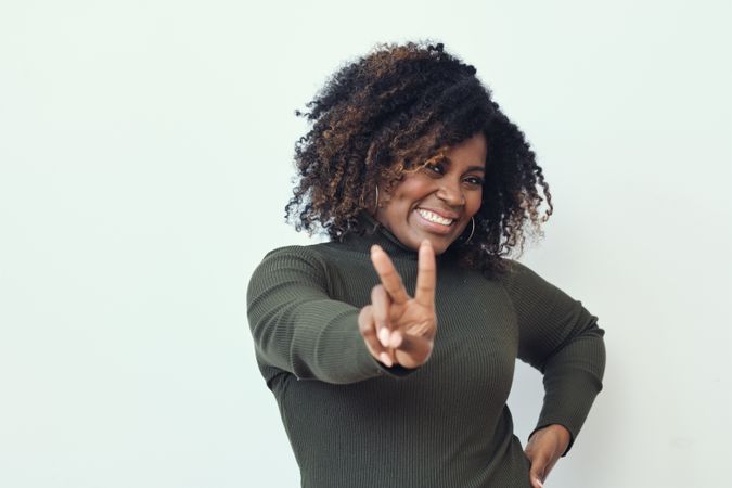 Smiling Black woman making the peace sign with her hands