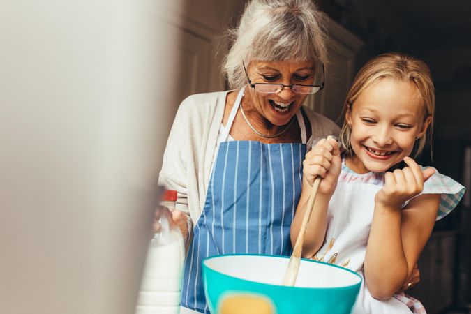 Happy grandmother and child mixing cake batter at home