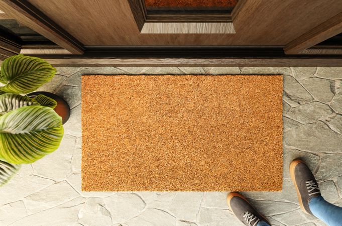 Overhead of blank doormat and shoes of a man standing on the porch at the front door.