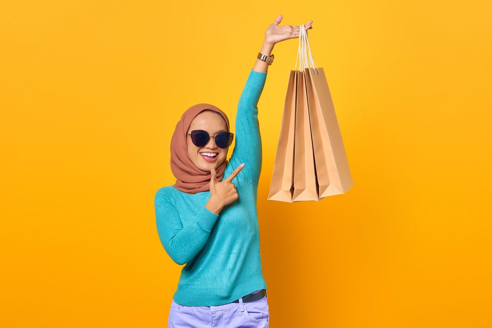 Fabulous Muslim woman holding shopping bags above her head