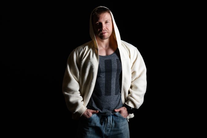 Man in hooded fleece jacket and jeans, hands in pockets.