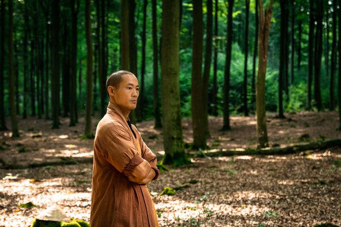 Asian guy in brown uniform resting in green forest