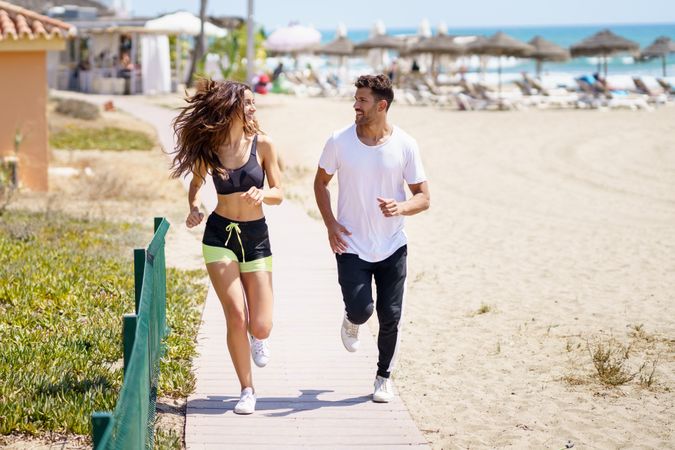 Man and woman jogging along beach path