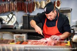 Man cutting ham behind counter in butcher shop 5klRj4
