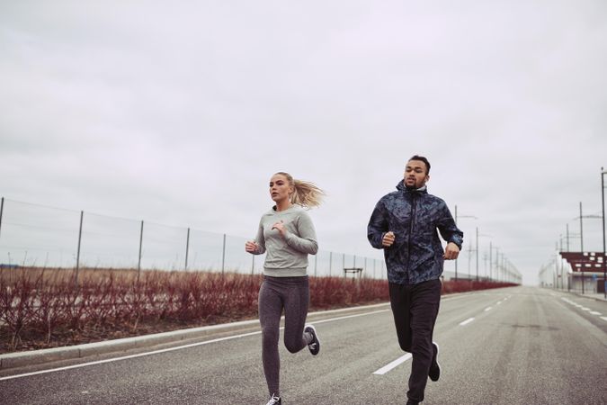 Fitness couple running together on empty road