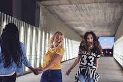 Joyful group of friends holding hands and walking together