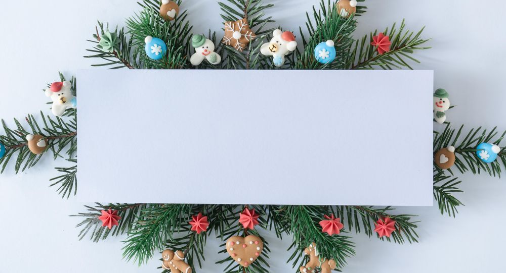 Pine tree branches with holiday decorations and blank center on blue pastel