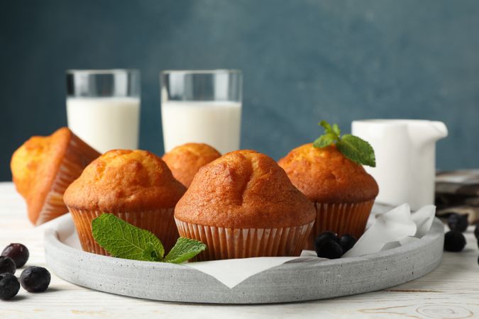 Composition with muffins and milk on plain wooden background