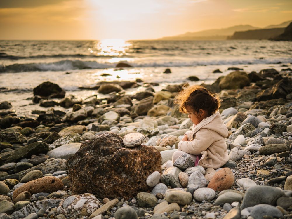 Girl sitting on rocky beach