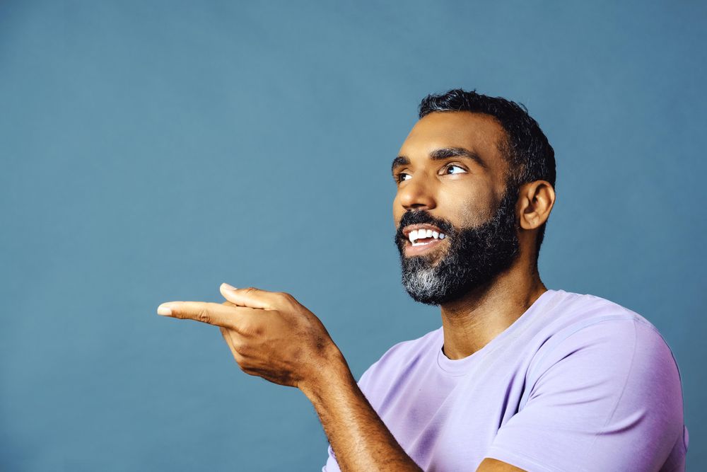 Side view of male speaking in purple t-shirt while gesturing to the side, copy space