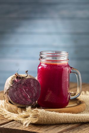 Red beet juice in a glass cup on the wooden table.