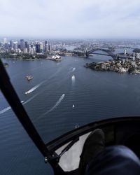 Rear view of pilot flying helicopter over large body of water toward city