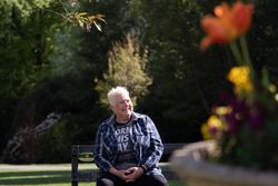 Woman with spiky grey hair smiling on park bench