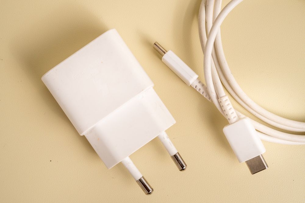A charger and a cable are laying on a yellow surface