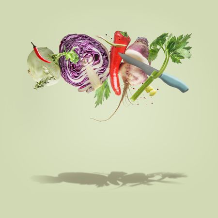 Creative food  levitation concept with flying various colorful vegetables and knife at pale green background. Healthy lifestyle