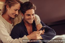 Couple looking at smart phone and smiling 4MmR14