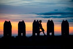 Silhouette of person between stone sculptures in sunset