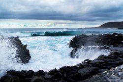 blue waves of ocean with foam texture against rocks