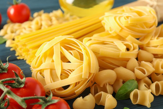 Composition with pasta ingredients on wooden background, space for text and closeup