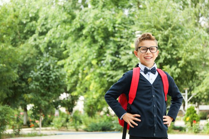 Boy in school uniform against greenery background, space for text