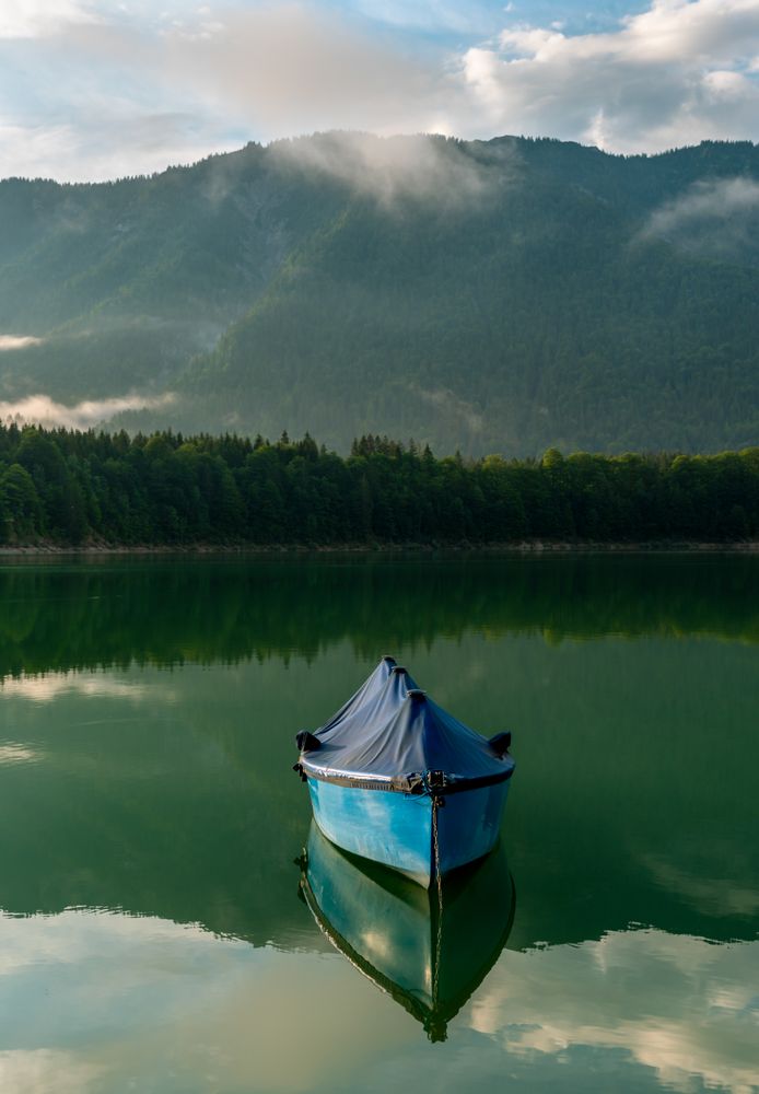 Fishing boat on Lake Sylvenstein and the mountain reflection in the water