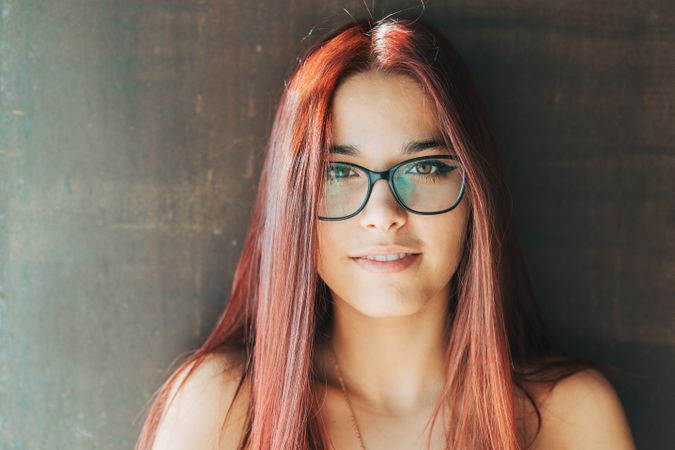 Woman in glasses leaning on wall