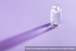 Tonic water with ice cubes in glass on purple background 4j69W4