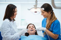 Dentist and assistant examining mouth of patient in chair with t