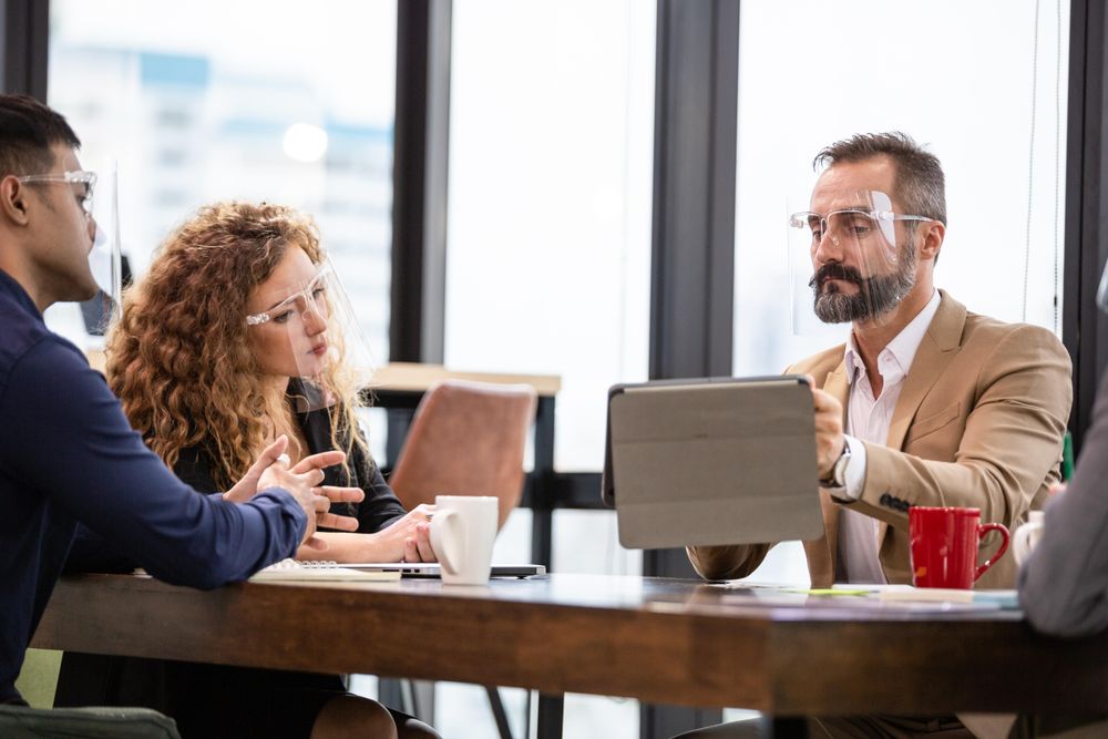 Man showing colleagues his work on a digital table