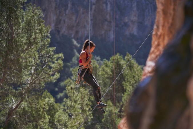 Woman rappeling down mountain on dynamic rope