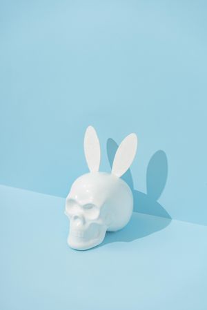 Skull with bunny ears on pastel blue background with copy space