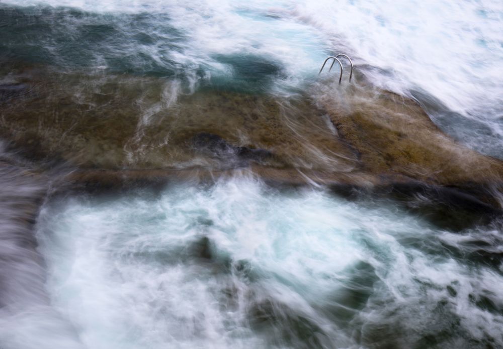 Stone shore with ladder between water