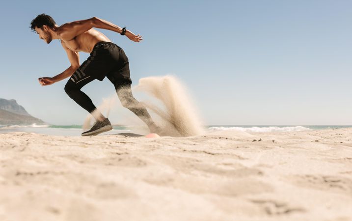 Man doing sprints on sand near the beach