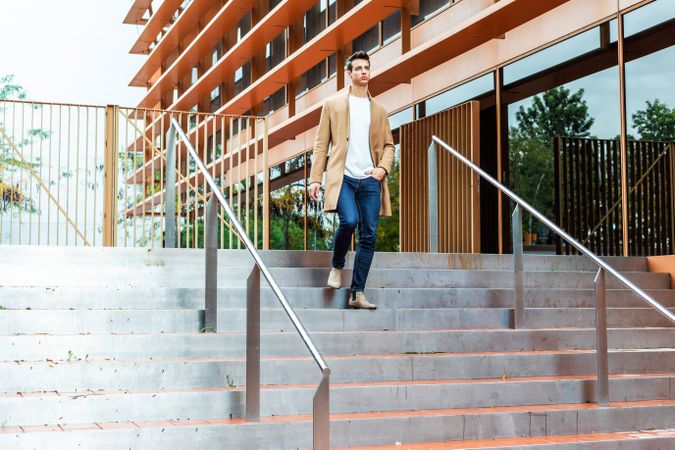 Man in autumn coat walking down staircase outside