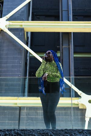 Black woman speaking on mobile phone in stylish wear in city