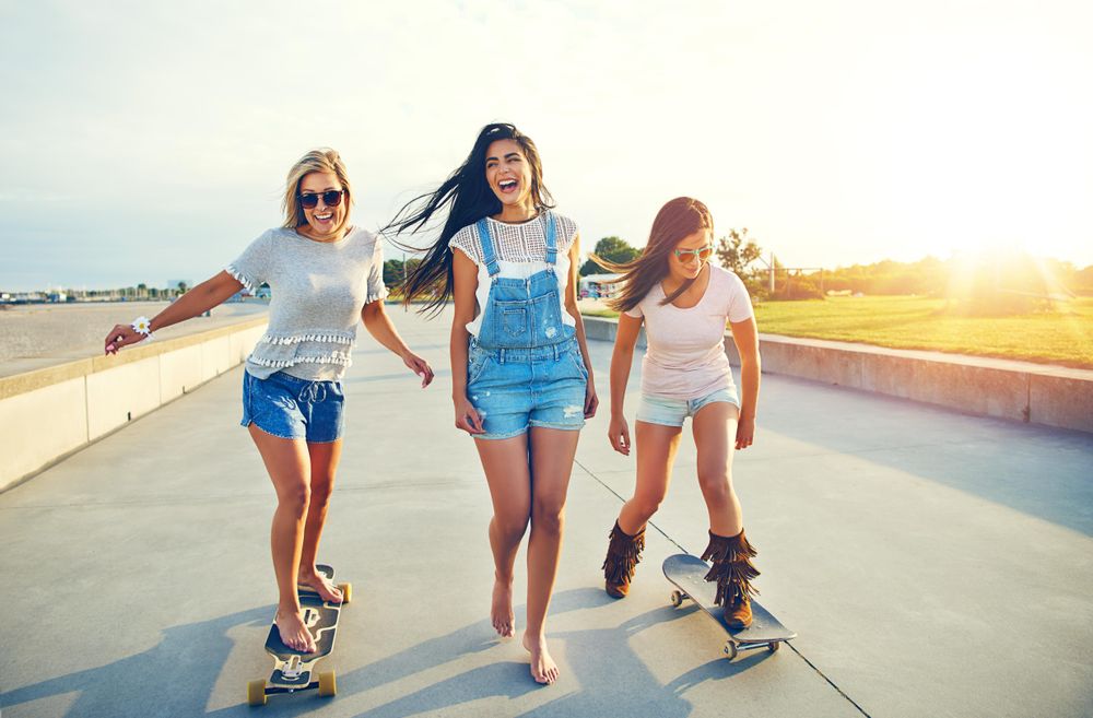 Multi-ethnic friends skateboarding on boardwalk near beach