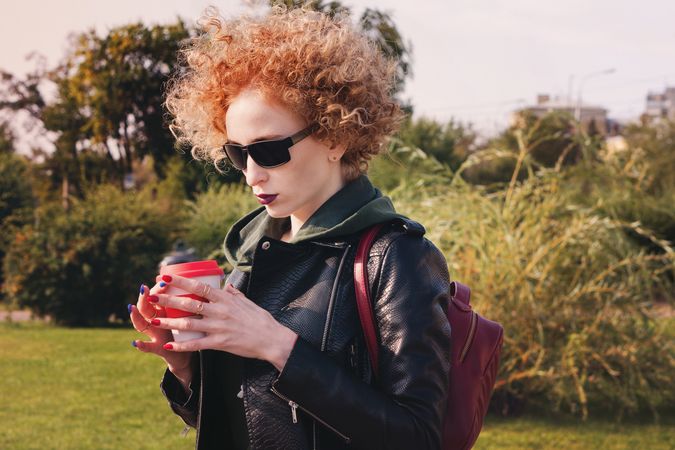 Curly haired woman with coffee outdoors