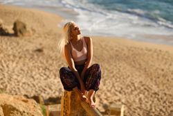 Blonde woman relaxing on post overlooking beach with face to the sun