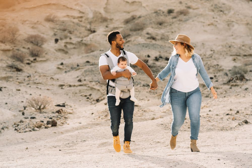 Diverse parents dancing while walking with baby